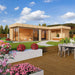 A colorful garden scene with vibrant flowers surrounds the sleek, modern GardenHouse24 USA Sauna Quieto 70 Garden Room