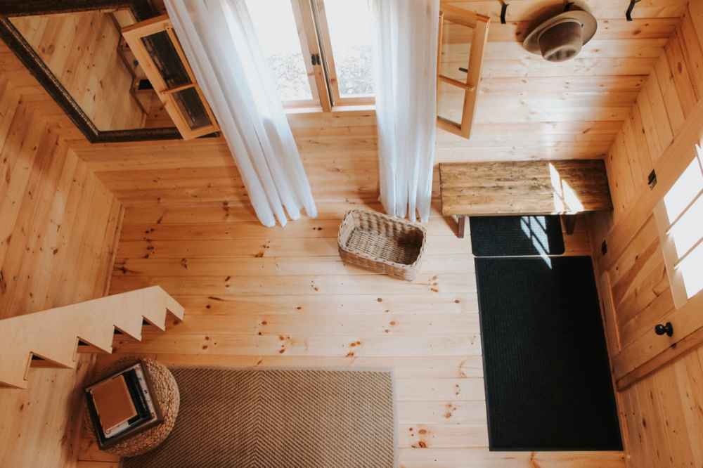 Sawmill Structures BlueWater Loft 160 70mm Garden Room entry area is seen from above, with wooden floors, a woven basket, and soft natural lighting from large windows