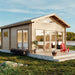 Sawmill Structures Edwin Lake House 70MM Garden Room sits gracefully in an open green area with a red chair on the porch and floor-to-ceiling windows