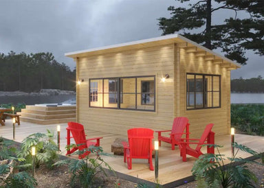 Sawmill Structures Eze Breeze Sunroom Cabin lit up at dusk surrounded by red Adirondack chairs on a spacious wooden deck