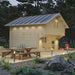Sawmill Structures GrandView 150 70MM Garden Room is seen from the opposite side, featuring a rustic picnic table and soft lighting under the roof eaves