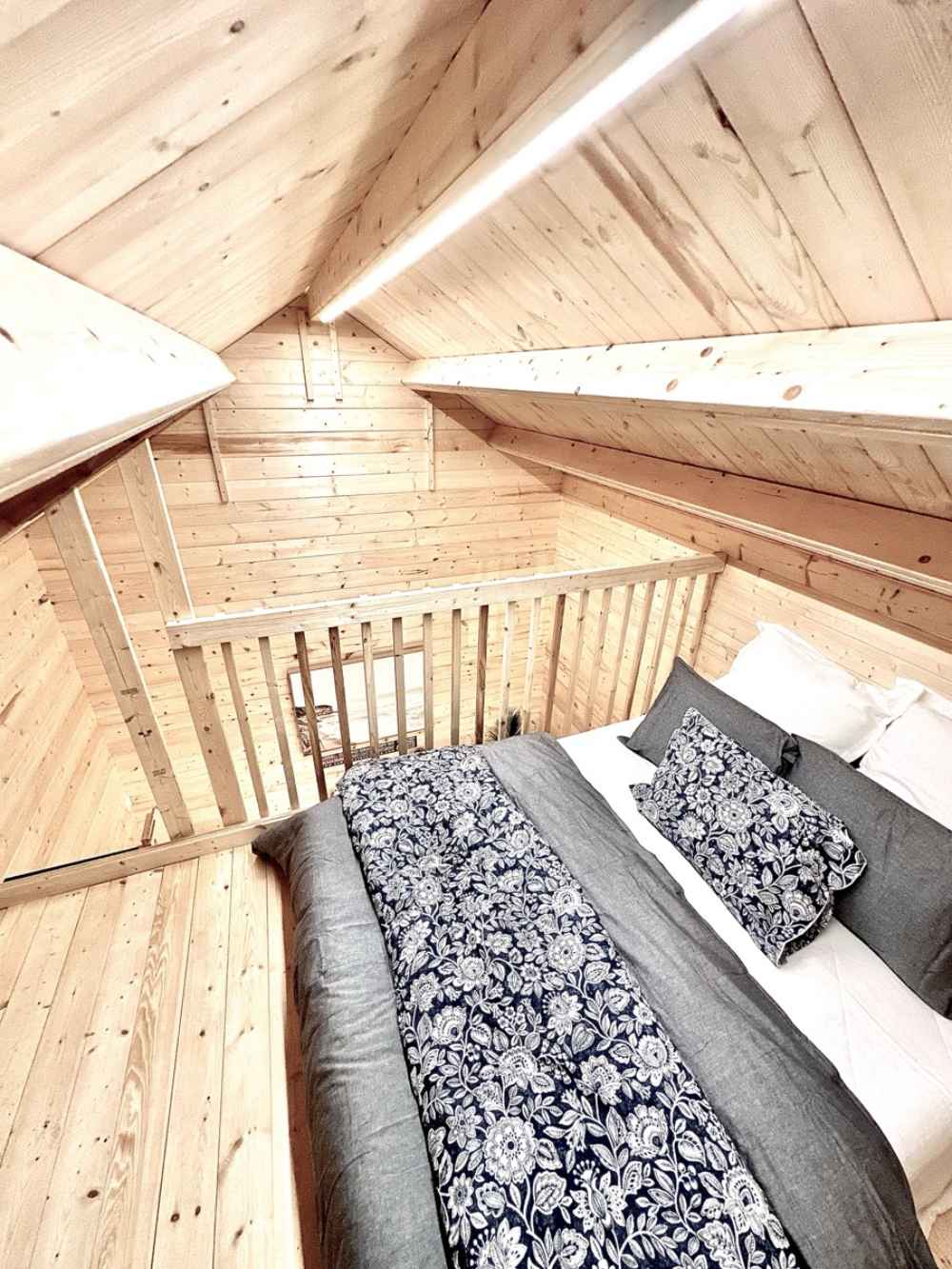 Sawmill Structures Ontario Grand Loft 107 SD Garden Room features a bright loft bedroom with sloped ceilings and a wooden railing overlooking the space below