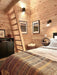 Sawmill Structures Ontario Grand Loft 107 SD Garden Room includes a main floor bedroom with a rustic ladder leading to the loft and framed art on pine walls