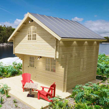 Sawmill Structures Ontario Grand Loft 107 SD Garden Room is a charming two-story wood cabin with a patio and red chairs by the lake