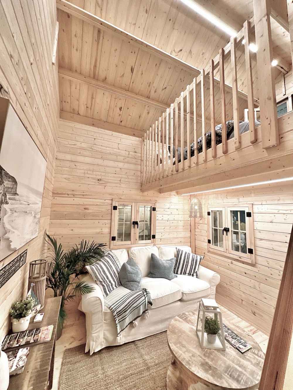 Sawmill Structures Ontario Grand Loft 107 SD Garden Room showcases its double-height living room with a view of the loft bed and white sofa below