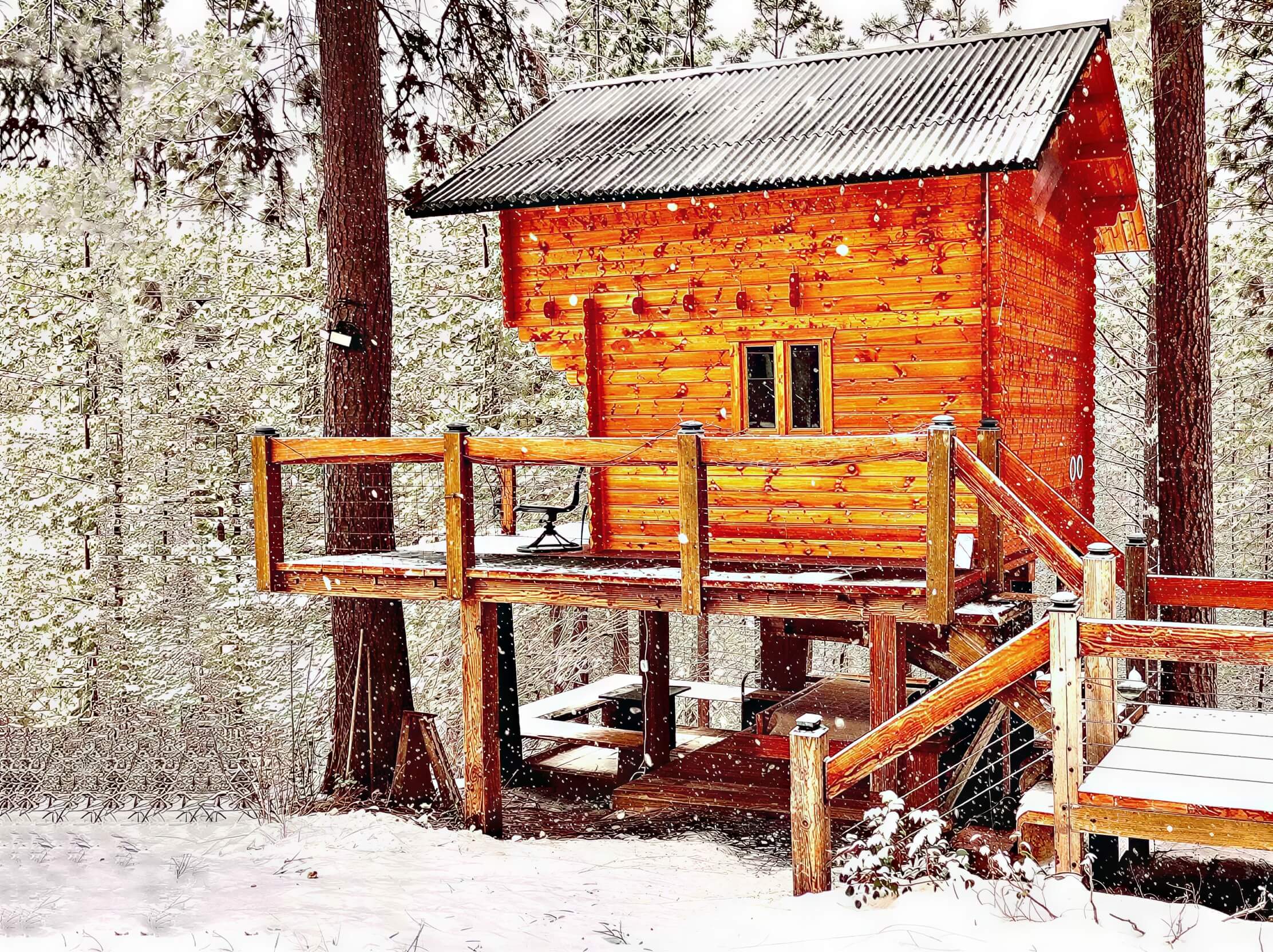 Sawmill Structures The Jumbo Grand Loft 130 SD Garden Room sits elevated on a snowy forest deck, its warm wooden exterior glowing against the winter landscape