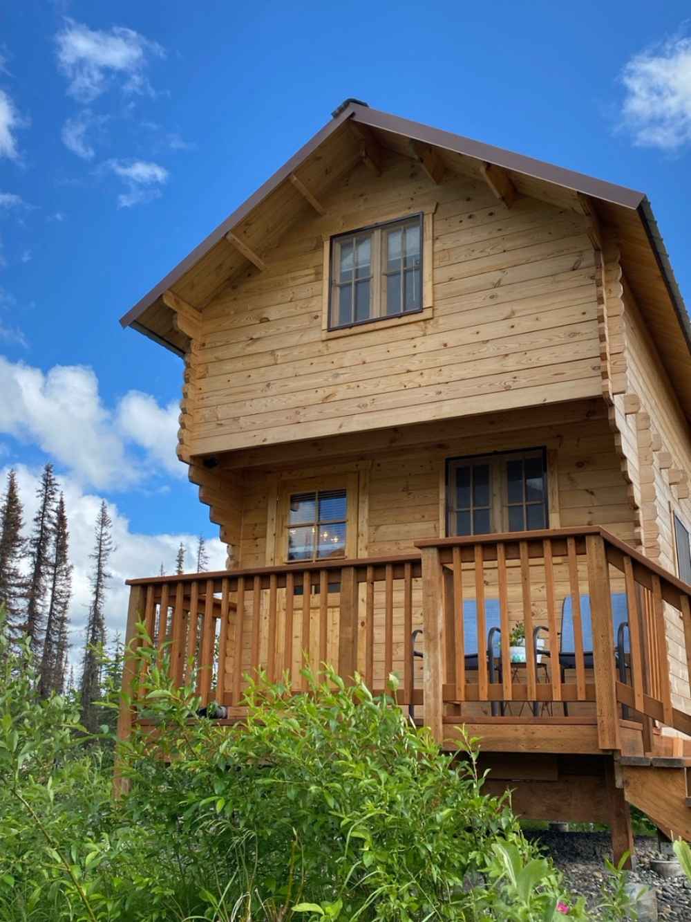 Sawmill Structures The Jumbo Grand Loft 130 SD Garden Room stands tall with a balcony and upper loft window surrounded by lush green landscape and blue skies