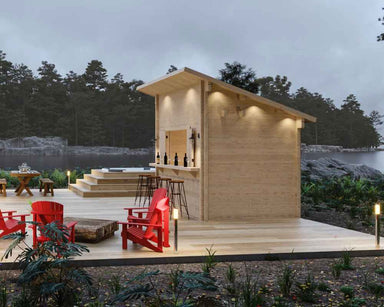 Sawmill Structures The Lakeside Versa Cabana 67 Garden Room stands on a lakeside deck at dusk, beautifully lit with warm lights and surrounded by Adirondack chairs and nature