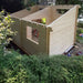 Sawmill Structures The Versa 240 70MM Garden Room is under construction with partially raised walls made of light timber in a wooded setting