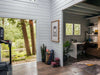 Sawmill Structures The Versa 240 70MM Garden Room opens to a home office with a desk, shelving, plants, and an adjacent fitness area