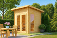 Sawmill Structures Versa Sauna glows warmly in sunlight beside a small dining table and chairs
