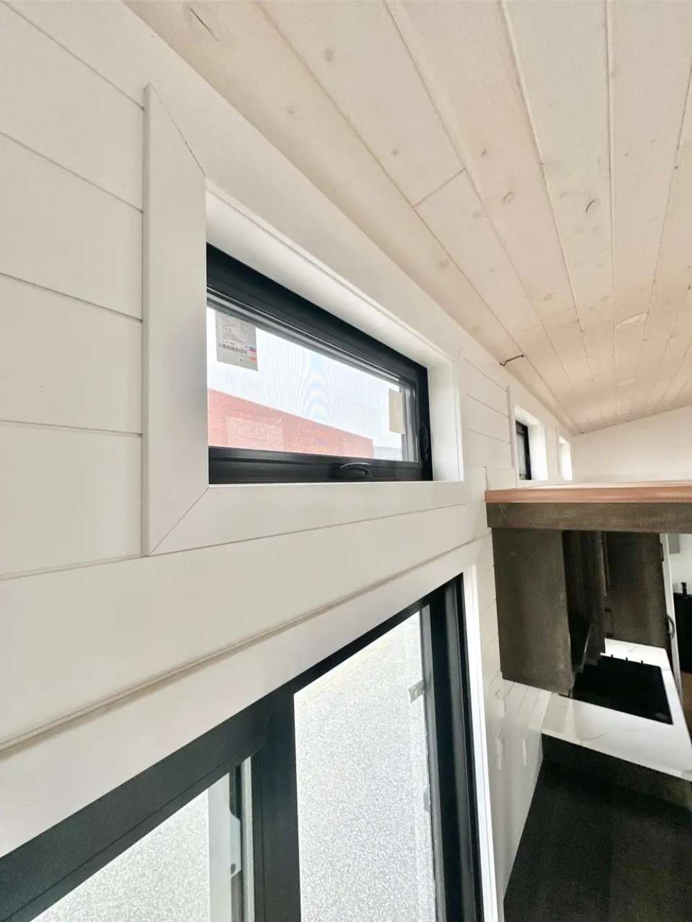 Sawmill Structures Wanderlove Tiny Home features slim black-framed windows near the ceiling
