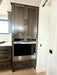 Sawmill Structures Wanderlove Tiny Home includes a stainless steel wall oven built into dark wood cabinetry next to a white sliding door