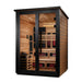 Seen from the front right, Golden Designs Kaskinen 6 Person 2 Tone Barn Hybrid Outdoor Sauna shows its cedar side wall, black trim and guarded stove inside