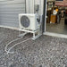 Senville Large Outdoor Ground Stand/Bracket for Mini Split (18000-36000 BTU) holding a mini split condenser outside a metal building on a gravel surface