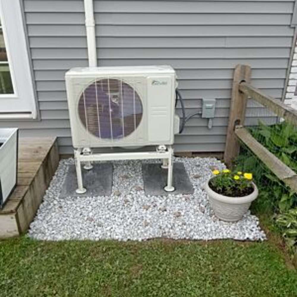 Senville Large Outdoor Ground Stand/Bracket for Mini Split (18000-36000 BTU) supporting a mini split outdoor unit on a raised stand over a gravel base beside a house