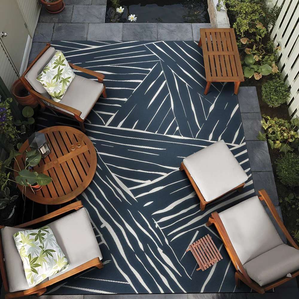 Set in a cozy patio layout, Couristan Dolce Indoor/Outdoor Rug - Parquet/Ink lies beneath wooden furniture and greenery