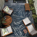 Set in a cozy patio layout, Couristan Dolce Indoor/Outdoor Rug - Parquet/Ink lies beneath wooden furniture and greenery