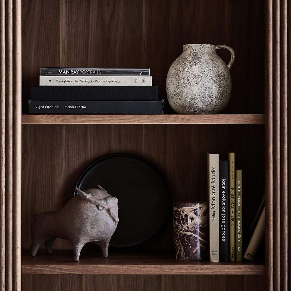 Shelf styling on Crate & Barrel Siena 34" Walnut Wood 4-Shelf Storage Bookcase with Drawer featuring books pottery and decorative accents
