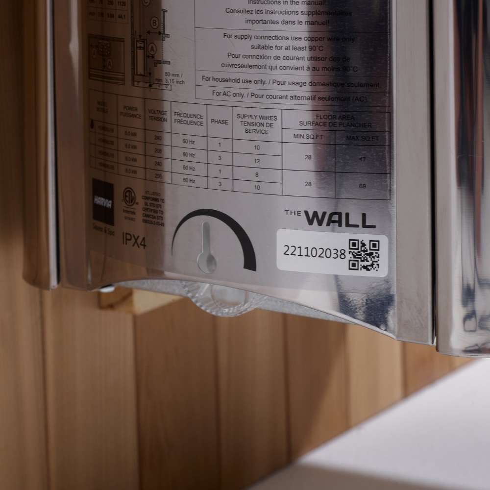 Side label on the stainless stove of Golden Designs Osla 6 Person Traditional Sauna showing a printed spec chart, a timer dial and The Wall logo