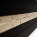 Side view highlighting the brass hinge hardware and textured black surface of GIK Acoustics ScreenPanel Vocal Screen