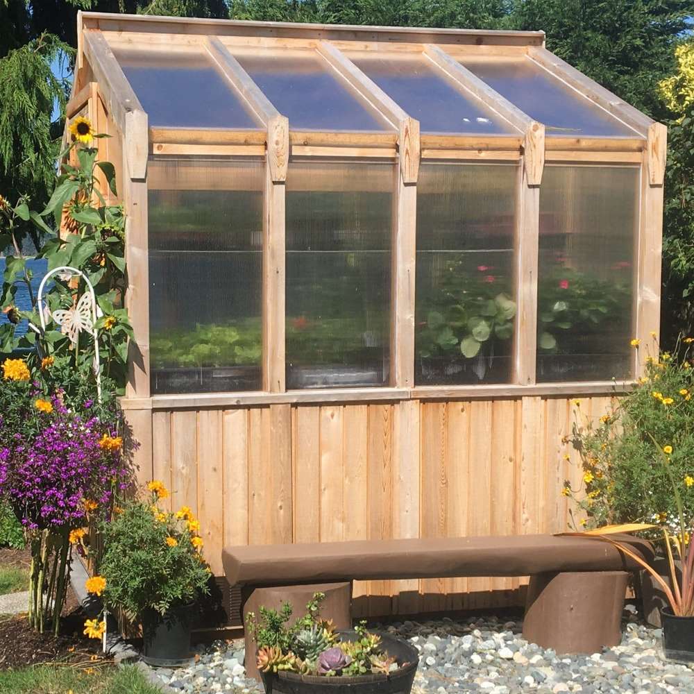 Side view of the cedar greenhouse with flowers and a bench displays the 8x8 Outdoor Living Today Western Red Cedar Greenhouse Kit