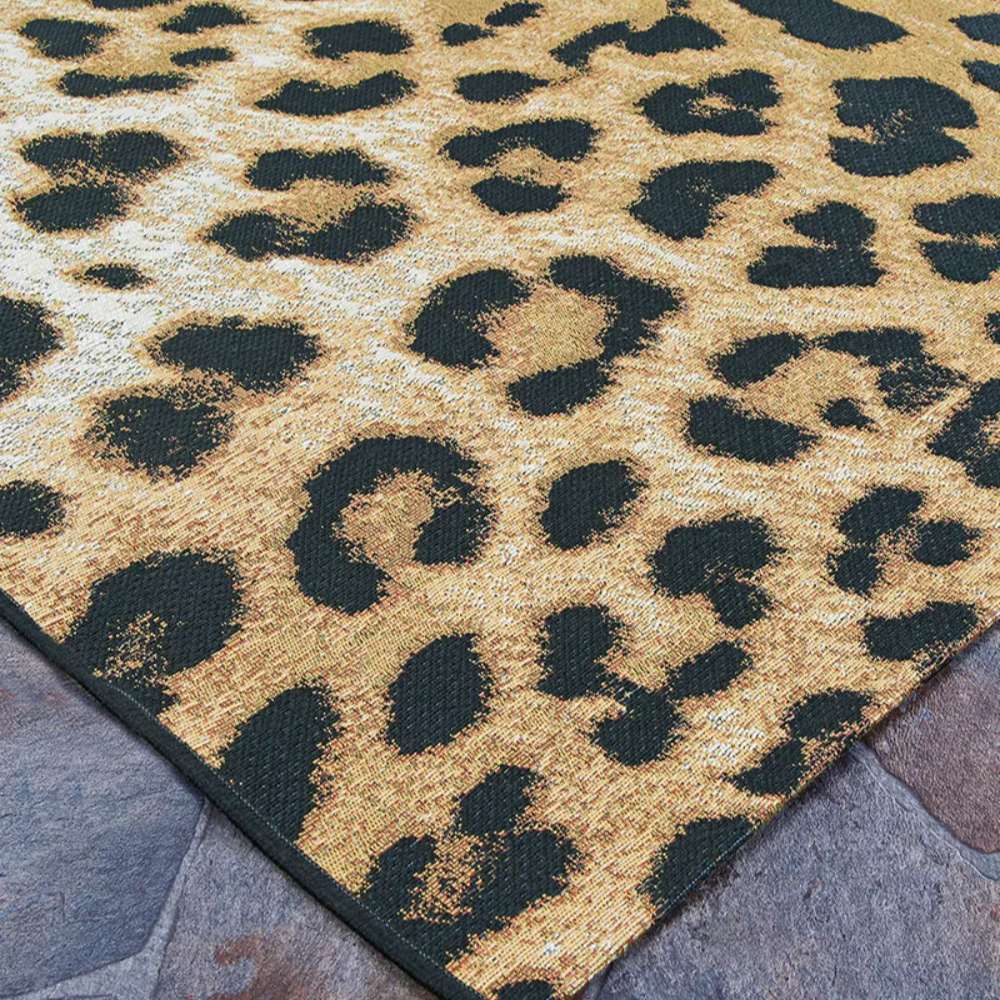 Side angle shot of Couristan Dolce Indoor/Outdoor Rug - Amur Leopard/New Gold highlights its black leopard print scattered over a golden and ivory