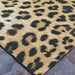 Side angle shot of Couristan Dolce Indoor/Outdoor Rug - Amur Leopard/New Gold highlights its black leopard print scattered over a golden and ivory