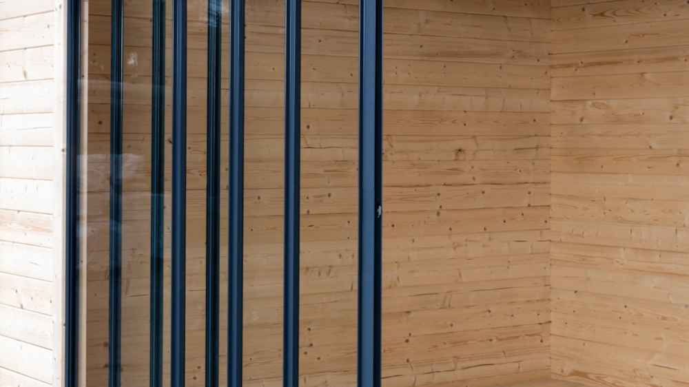Side view of the closed sliding glass panels showing the wooden interior walls of the GardenHouse24 USA Q Bic ALU 44A SD Garden Room