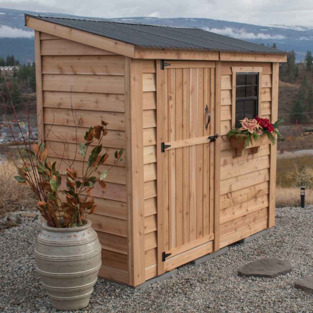 Single Door Metal Roof Outdoor Living Today 8×4 SpaceSaver Lean-To Cedar Shed displays a rustic cedar finish, metal roof, and window flower box beside a decorative planter on gravel