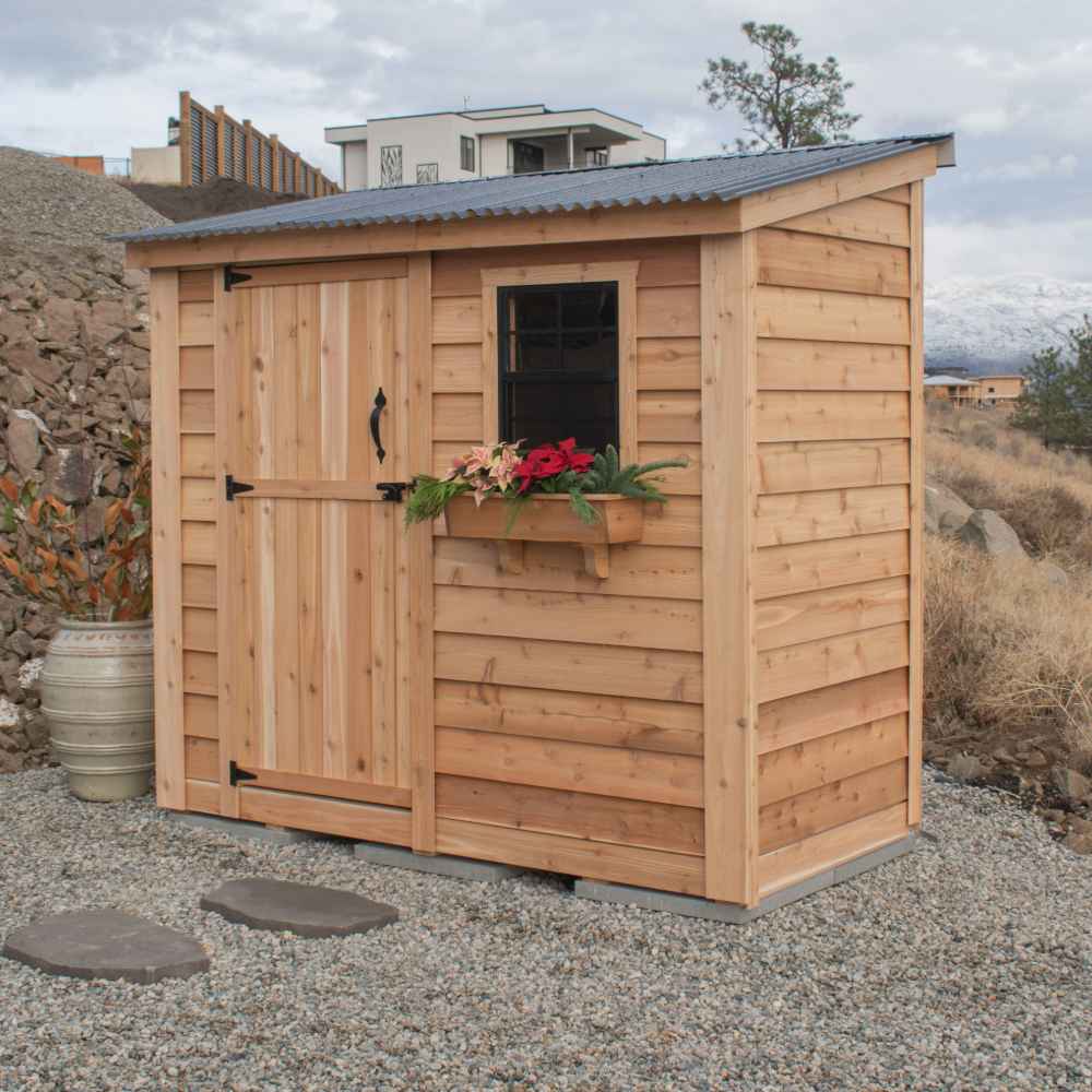 Single Door Metal Roof Outdoor Living Today 8×4 SpaceSaver Lean-To Cedar Shed is set on gravel with a slanted metal roof, front window with flowers, and vertical plank door under cloudy skies
