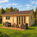 Skive 70 wooden garden room with glass-panel double doors and wicker patio seating on a sunny landscaped lawn.