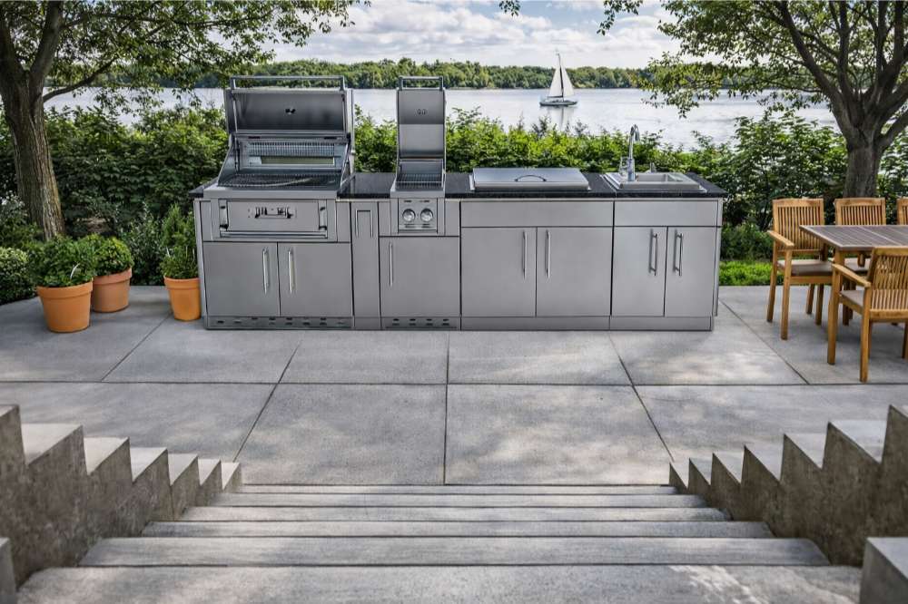 Sleek lakeside outdoor kitchen featuring the Sunstone Alamo 10ft Outdoor Cabinet Island Package with Hybrid Grill