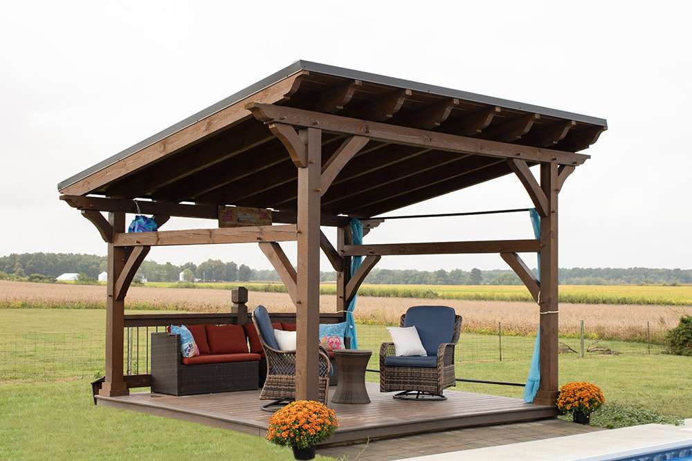 Spacious Brookside Timber Frame Rose Beam Pavilion with outdoor seating on a deck in a rural landscape
