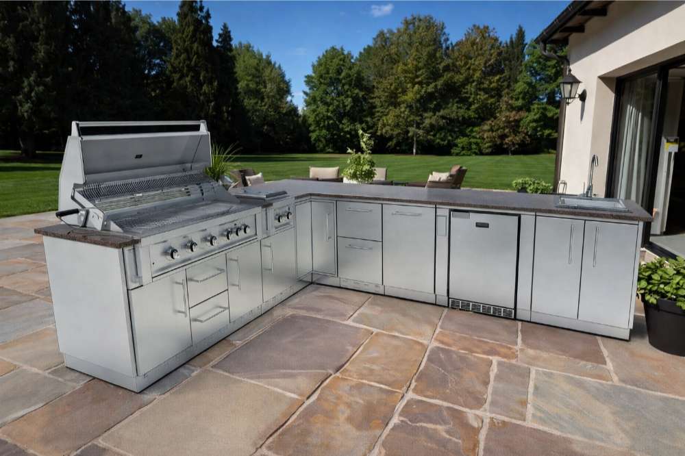 Spacious backyard with Sunstone Rancher L-Shaped 8′11″ × 11′ Outdoor Kitchen Package on a stone patio