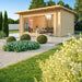 GardenHouse24 USA Starla 44E ALU ISO Garden Room is beautifully staged in a landscaped yard with sunlight pouring through its glass front into the inviting interior