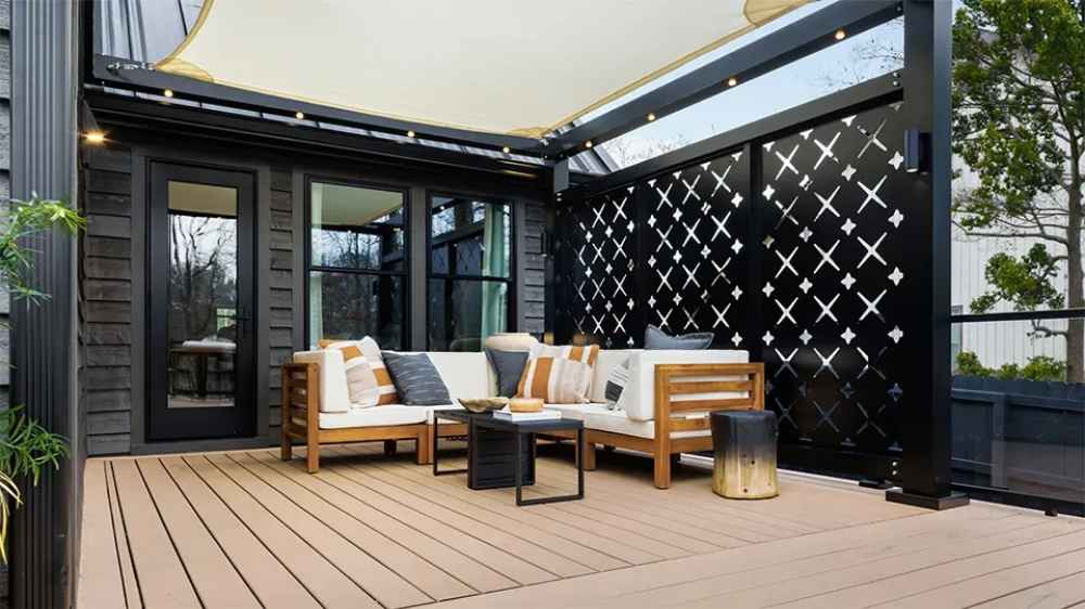 Structureworks Solis Trex Pergola shades an urban courtyard lounge area with wooden outdoor furniture and potted plants