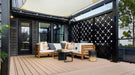 Structureworks Solis Trex Pergola shades an urban courtyard lounge area with wooden outdoor furniture and potted plants