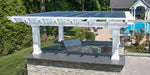Structureworks Williamsburg Fiberglass Pergola with a clear roof panel shelters an outdoor kitchen island by the pool