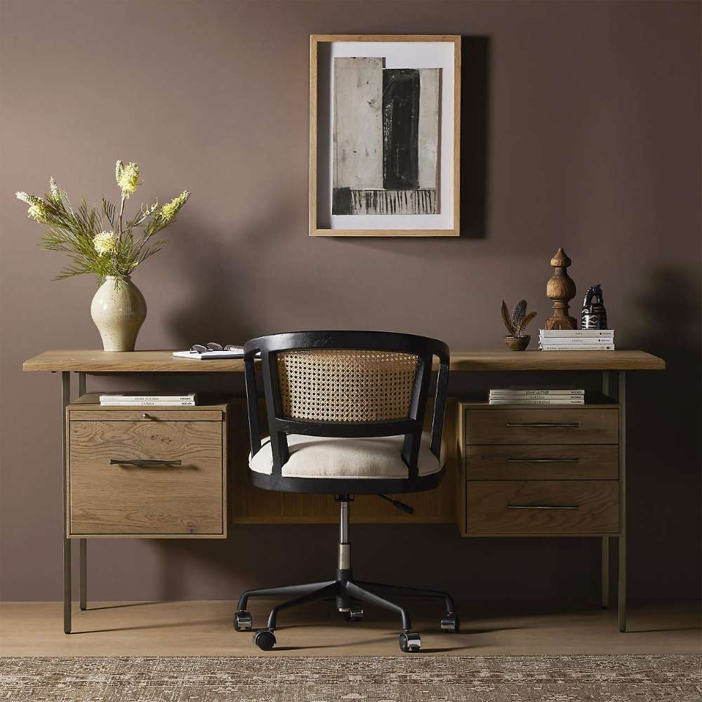 Styled in a warm home office, Crate & Barrel Sedgwick Solid Oak Wood Desk with Storage is paired with a woven office chair and decorative accessories