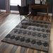 Styled in a modern living room, Momeni Andes Indoor Rug - AND-1 Charcoal adds a bold geometric touch to hardwood floors