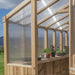 Sunlight shines through panels onto plants inside the Outdoor Living Today Western Red Cedar Greenhouse Kit