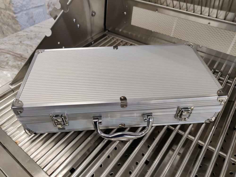 Sunstone 10 Piece Stainless Steel BBQ Tool Set w Carry Case is closed, showing a sleek silver metal case with a handle and secure clasps, resting on a grill