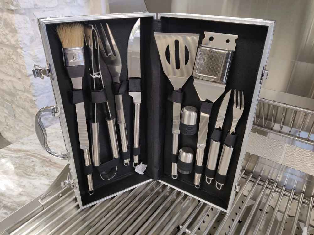 Sunstone 10 Piece Stainless Steel BBQ Tool Set w Carry Case is opened on a grill, showing neatly arranged tools including a spatula, tongs, knives, and basting brush