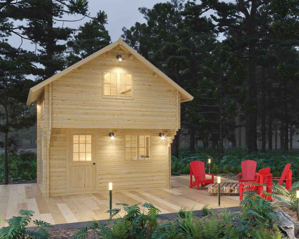 Surrounded by tall pines, the Sawmill Structures The Jumbo Grand Loft 130 SD Garden Room glows softly in the evening with warm lights and a front deck