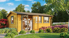 Surrounded by vibrant flowers and green shrubs, the GardenHouse24 USA Miriam 44A Classic Garden Room sits in a lush garden with a clear glass door revealing a cozy interior