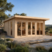 Rectangular light wood cabin with glass doors and windows on a stone patio, showing people inside the Taunus 70 suite.