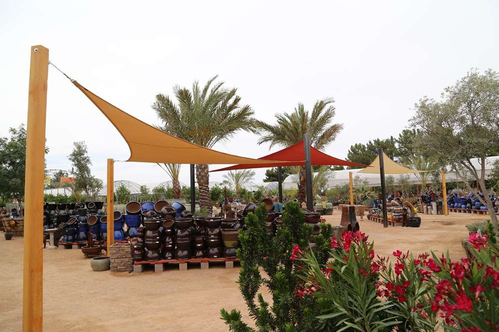 Tenshon Right Triangle Shade Sail stretched between wooden and metal posts in a garden center