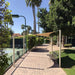 Tenshon Square Shade Sail stretches above a tennis court walkway, creating comfortable shade for benches beneath palm trees