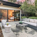 The Couristan Castille Indoor/Outdoor Rug - Canvas/Glacier lies under outdoor furniture on a stylish patio